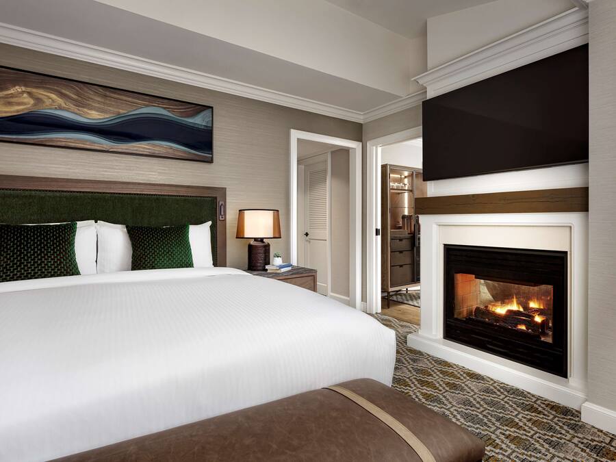 Une chambre d’hôtel dotée d’un grand lit, d’une cheminée et d’un décor moderne.