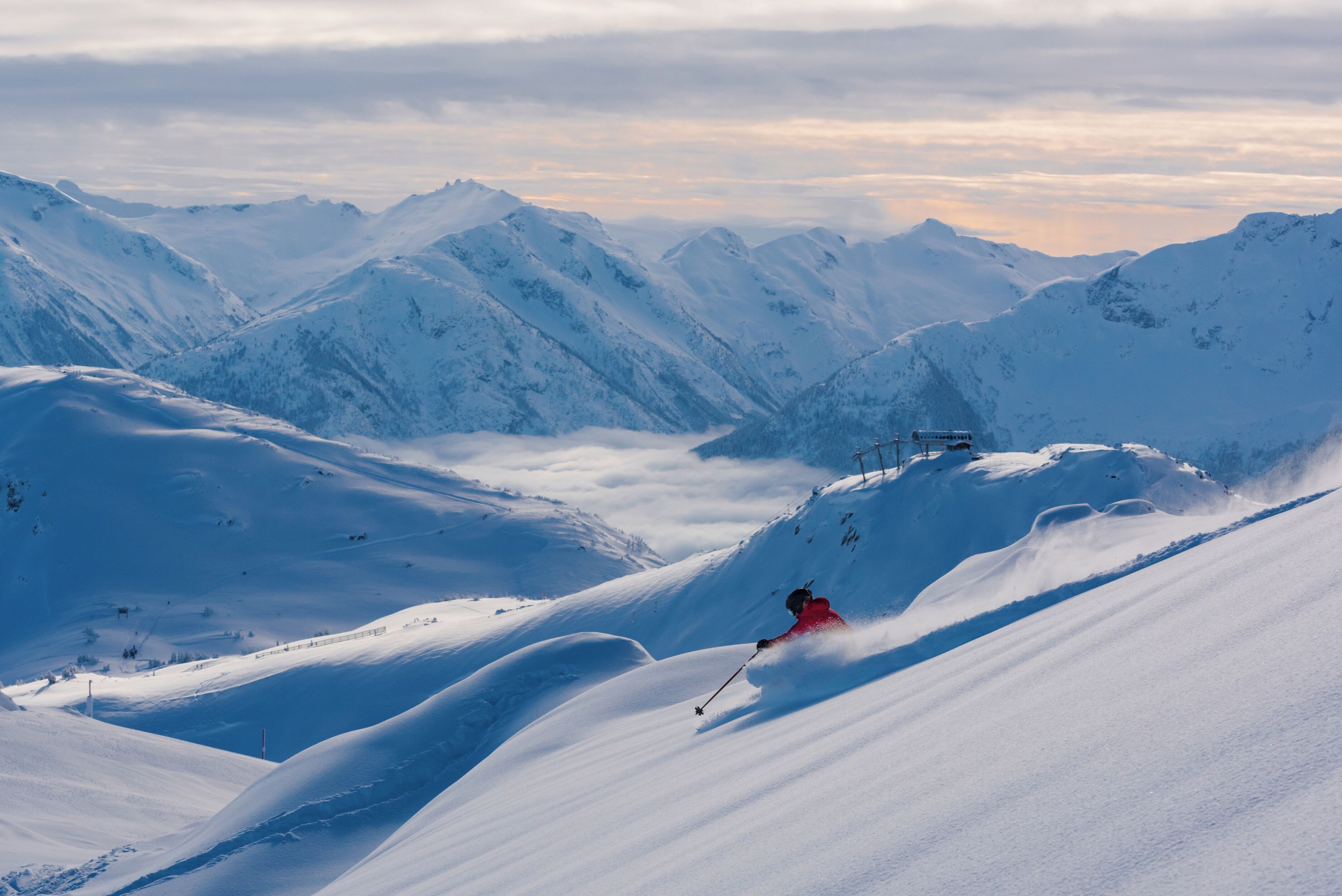 A snowy mountain landscape with a skier in motion.