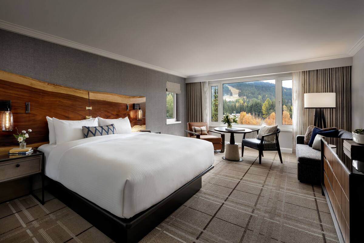 Une chambre d’hôtel avec un grand lit, une table à manger, un canapé et une vue sur l’extérieur.