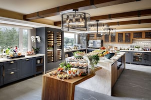 Una cocina moderna con una isla central, estanterías empotradas para vinos y un amplio ventanal con vistas a zonas verdes.