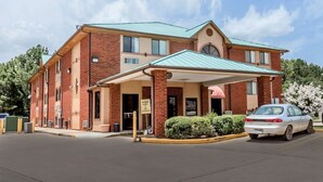 A two-story brick building with a green roof, a covered entrance, and a sign indicating low clearance.