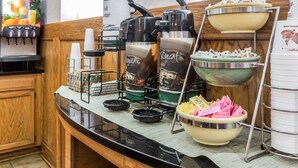 A kitchenette with a coffee maker, a tea kettle, a coffee dispenser, and a bowl of sugar packets.