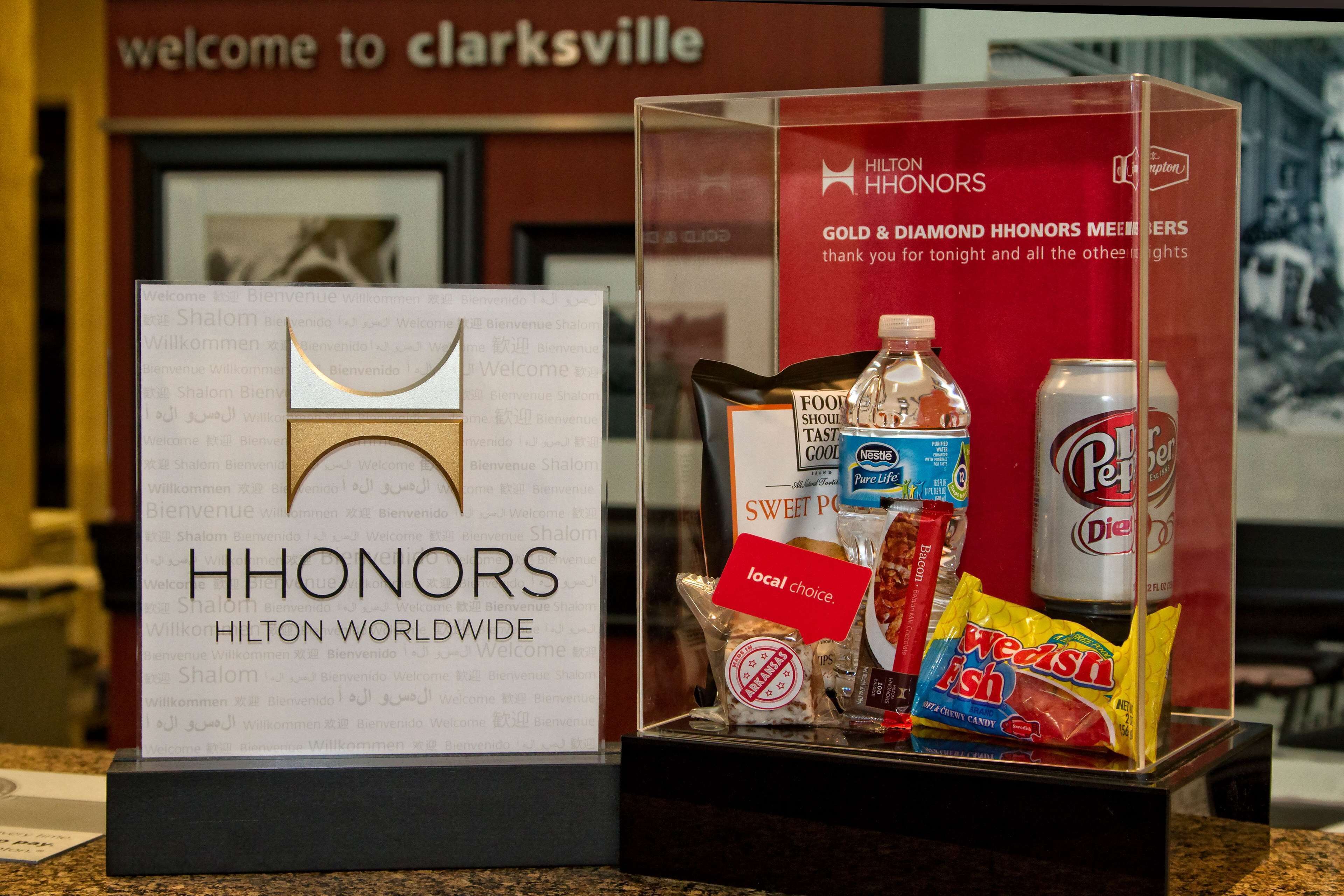 A display of Hilton Honors Gold & Diamond members' gifts, including a water bottle, a can of Diet Pepsi, and snacks.