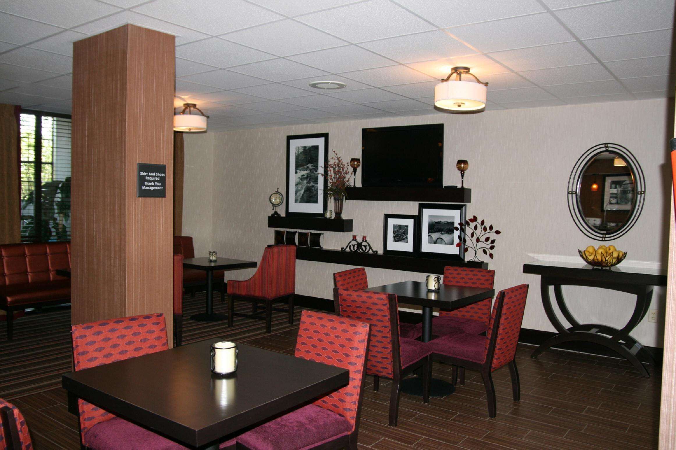 Eine Hotellobby mit Sitzbereichen, Tischen und einem an der Wand befestigten Fernseher.