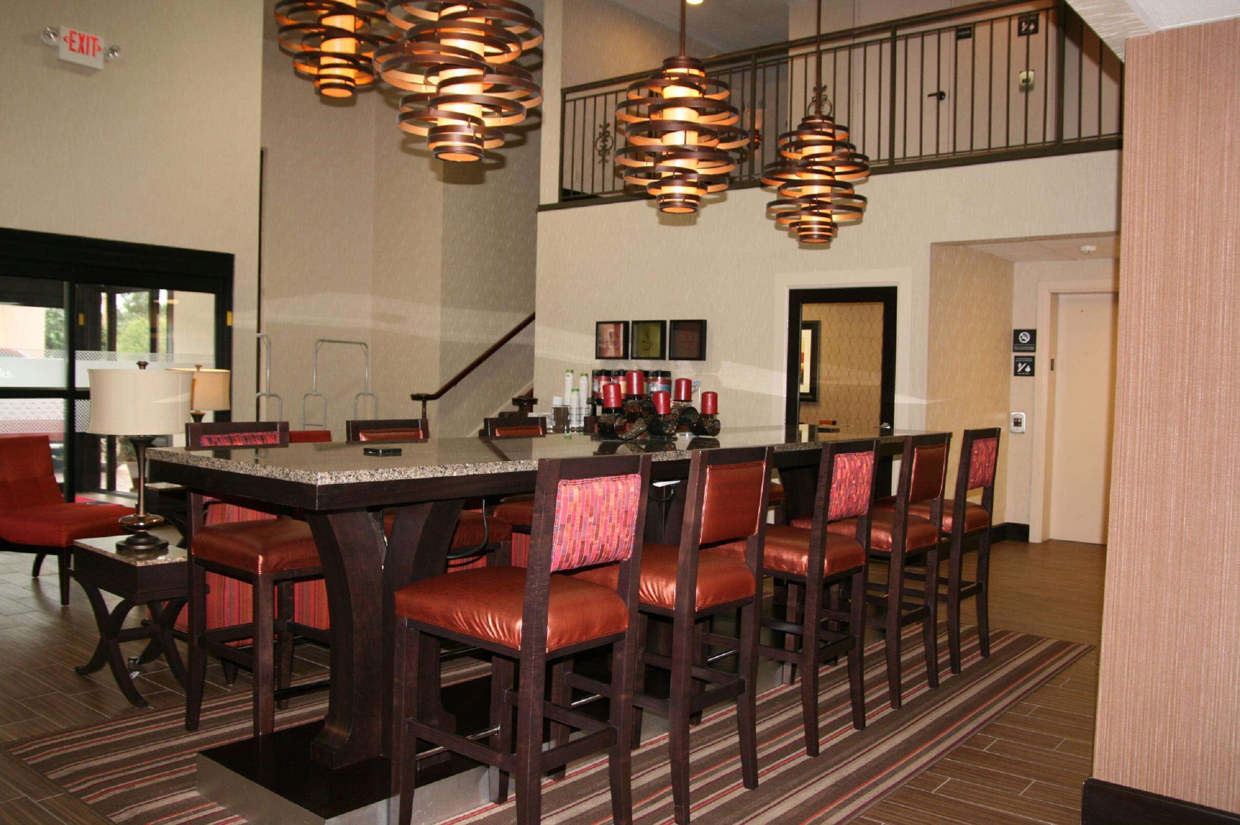 A dining area with a long table, multiple chairs, and hanging pendant lights.