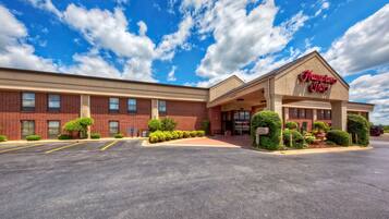 A Hampton Inn with a brick facade, a covered entrance, and a parking lot.
