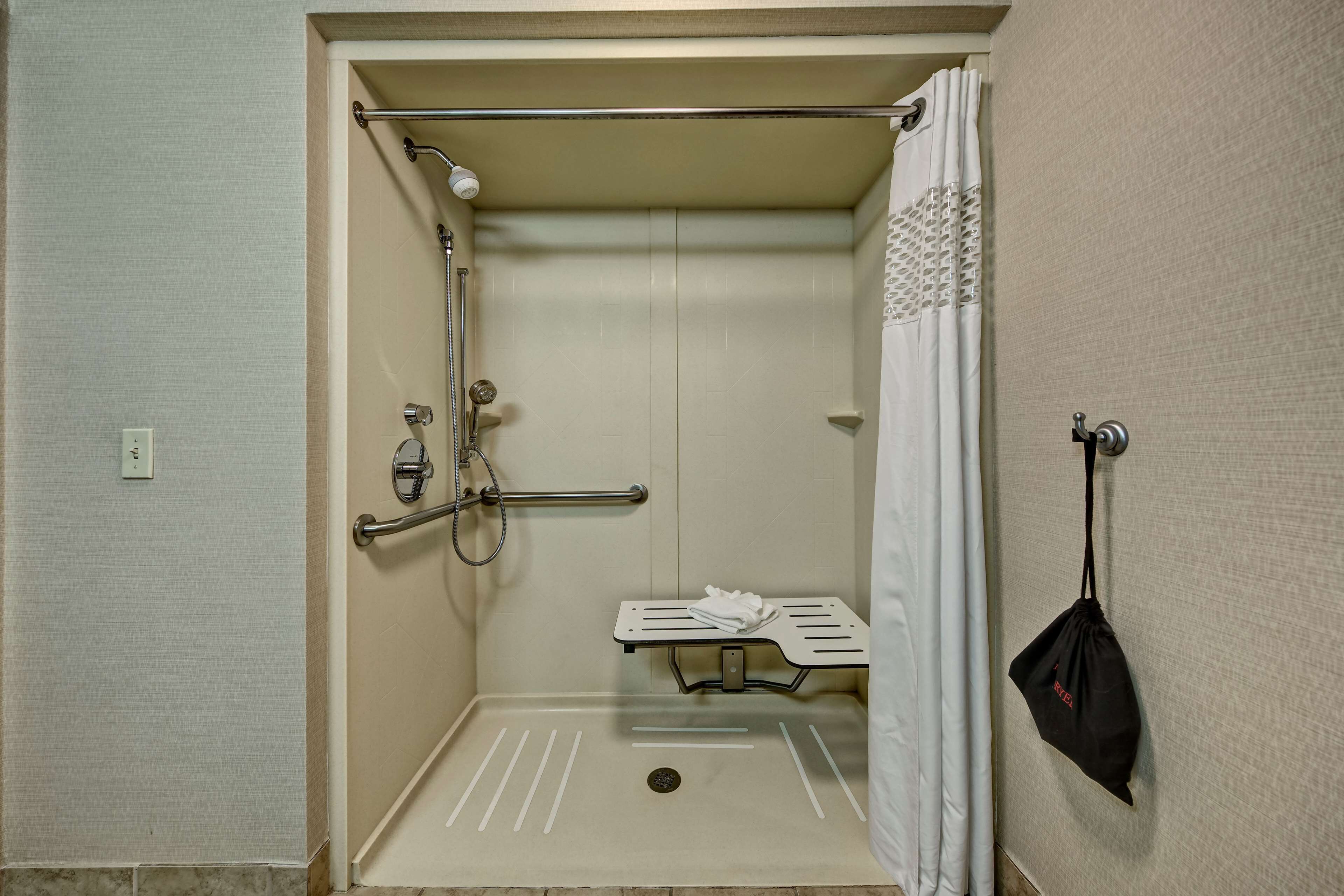 Une petite cabine de douche fermée, équipée d’une barre d’appui, d’un porte-serviettes et d’un pommeau de douche.