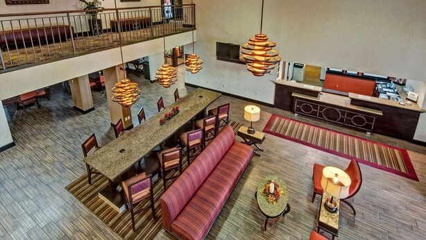Un'ampia hall d'hotel con soffitto alto, un'area salotto centrale e una reception.