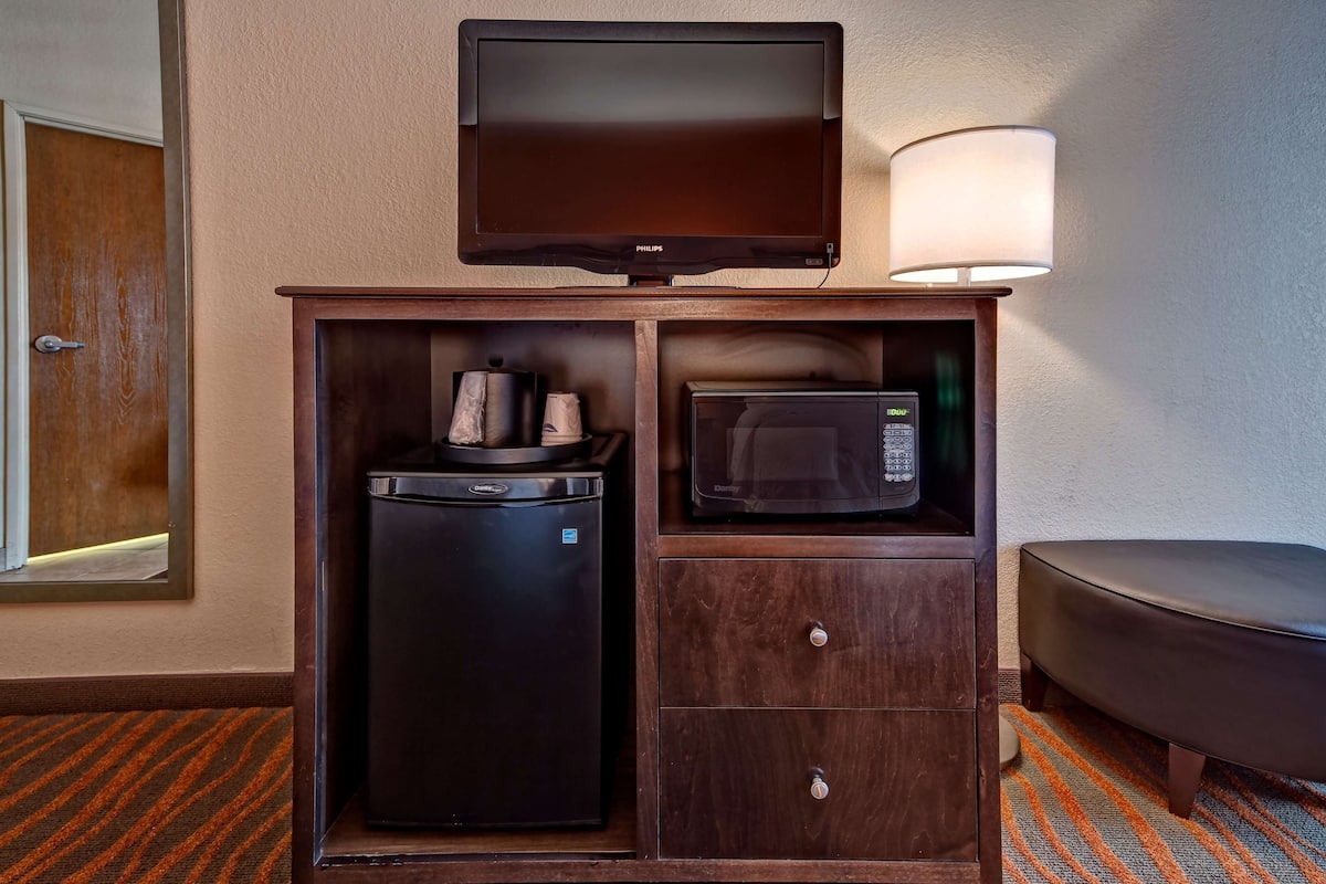 A compact minibar with a television, microwave, and coffee maker.