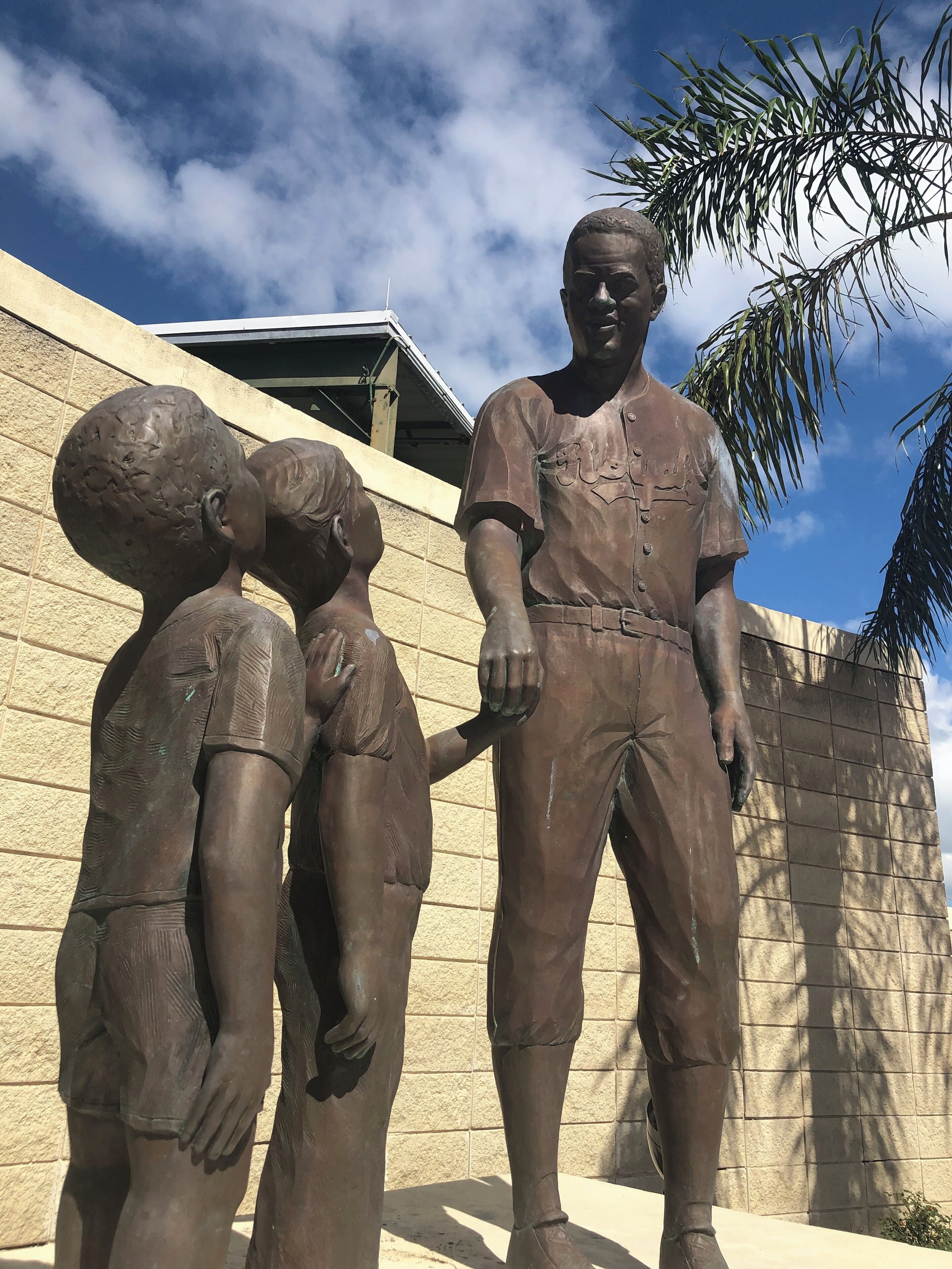A bronze statue of a man and two children in a courtyard with a building in the background.