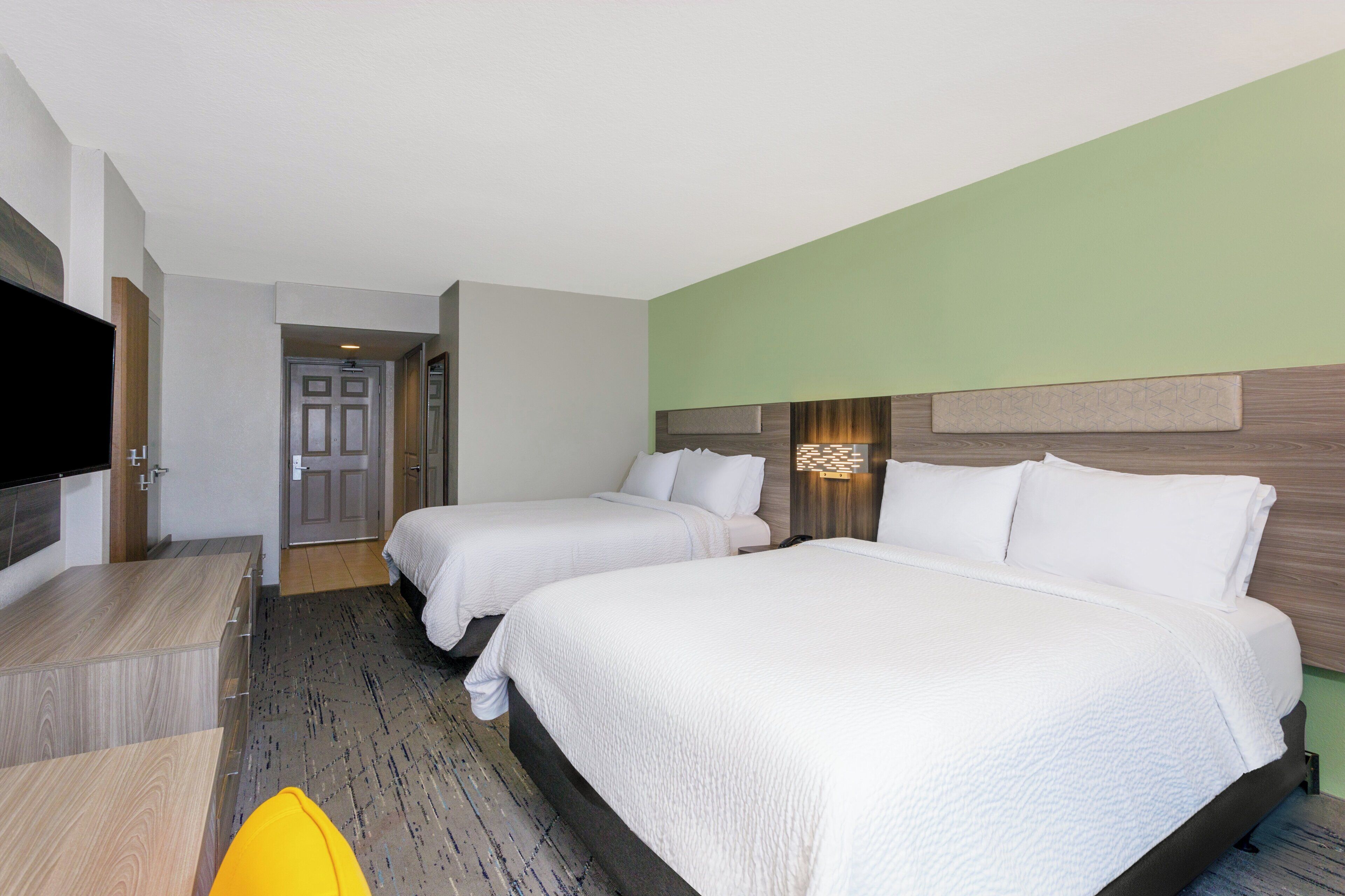 A hotel room with two beds, a flat-screen TV, a desk, and a chair.