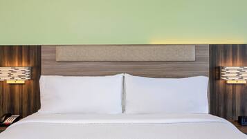 Un lit bien fait, avec du linge de lit blanc, une tête de lit en bois et deux lampes de chevet.