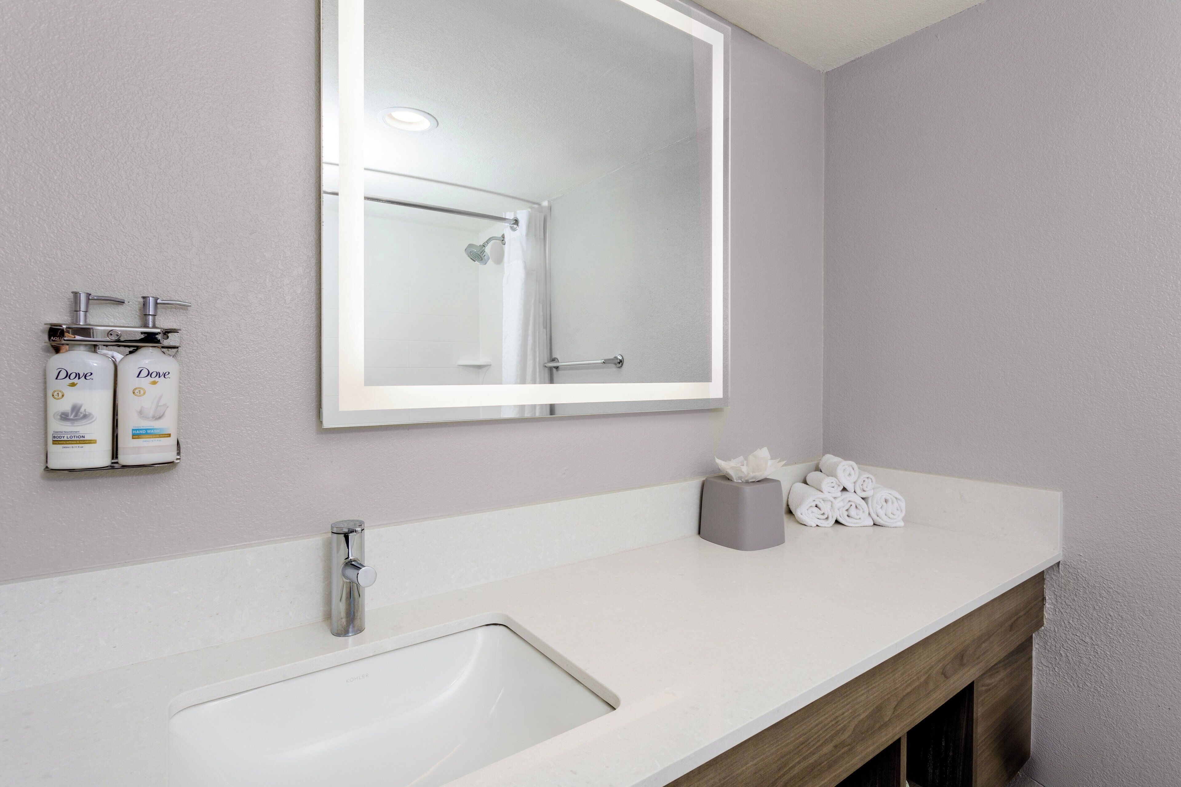 A modern bathroom with a large mirror, a sink, and toiletries.