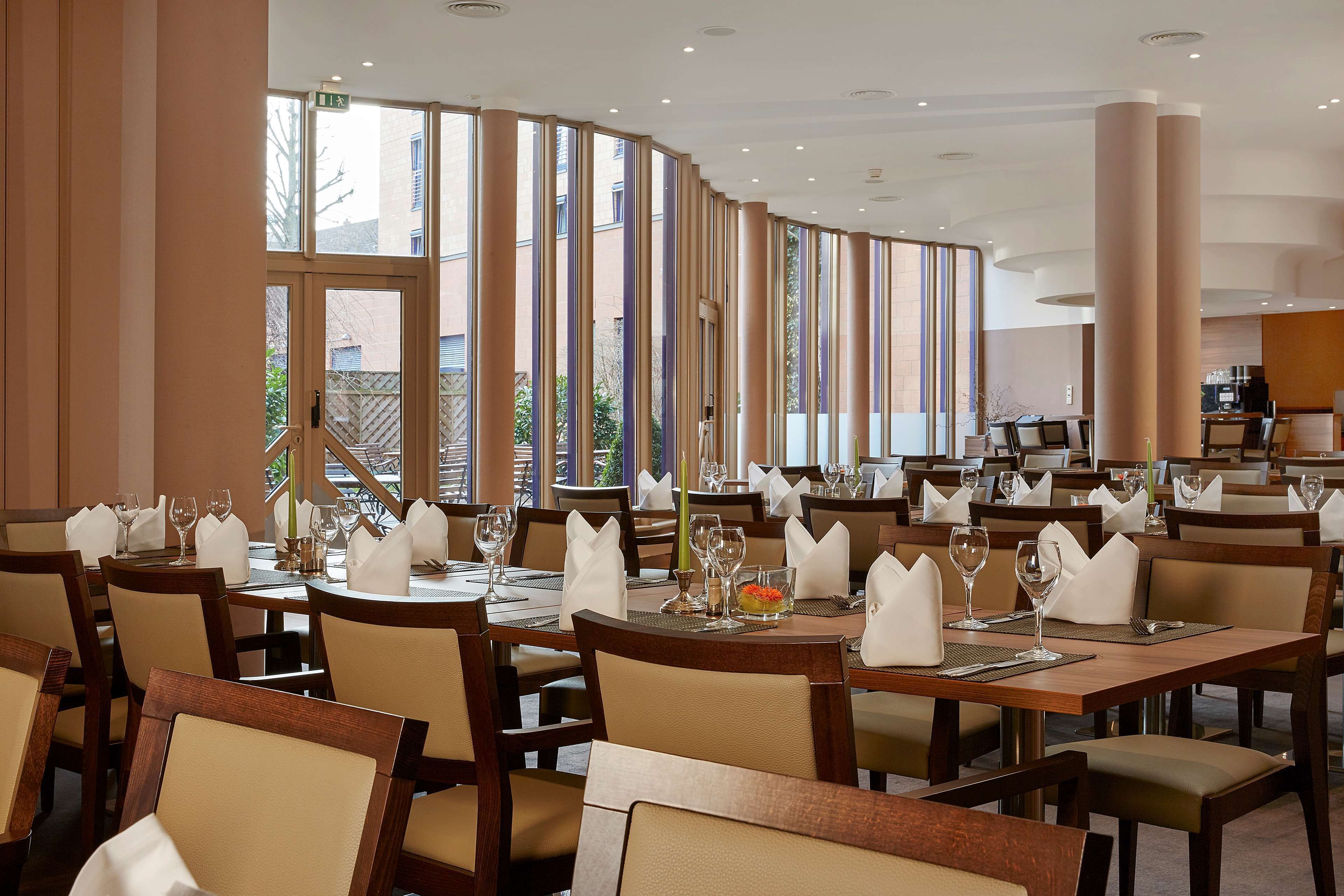 A restaurant with multiple tables set for dining, large windows, and a modern interior design.