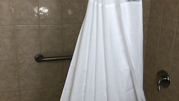 Une baignoire avec un rideau de douche blanc dans une salle de bain carrelée.