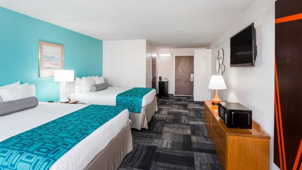 A hotel room with two beds, a TV, a microwave, and a desk with a lamp. - Howard Johnson by Wyndham Winter Haven FL (Winter Haven)