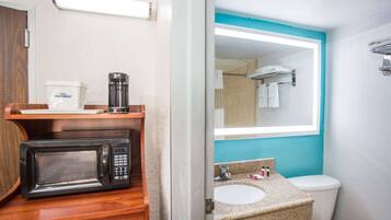A compact bathroom with a microwave, coffee maker, sink, and toilet.