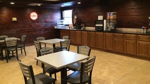 A restaurant with wooden walls, a neon sign, tables, chairs, a kitchen area, and a tiled floor. - Howard Johnson by Wyndham Winter Haven FL (Winter Haven)