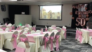 A conference room with tables set for an event, featuring pink and white tablecloths and chairs with pink sashes. - Howard Johnson by Wyndham Winter Haven FL (Winter Haven)