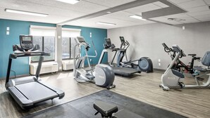 Un gimnasio con cintas de correr, elípticas y una bicicleta estática.