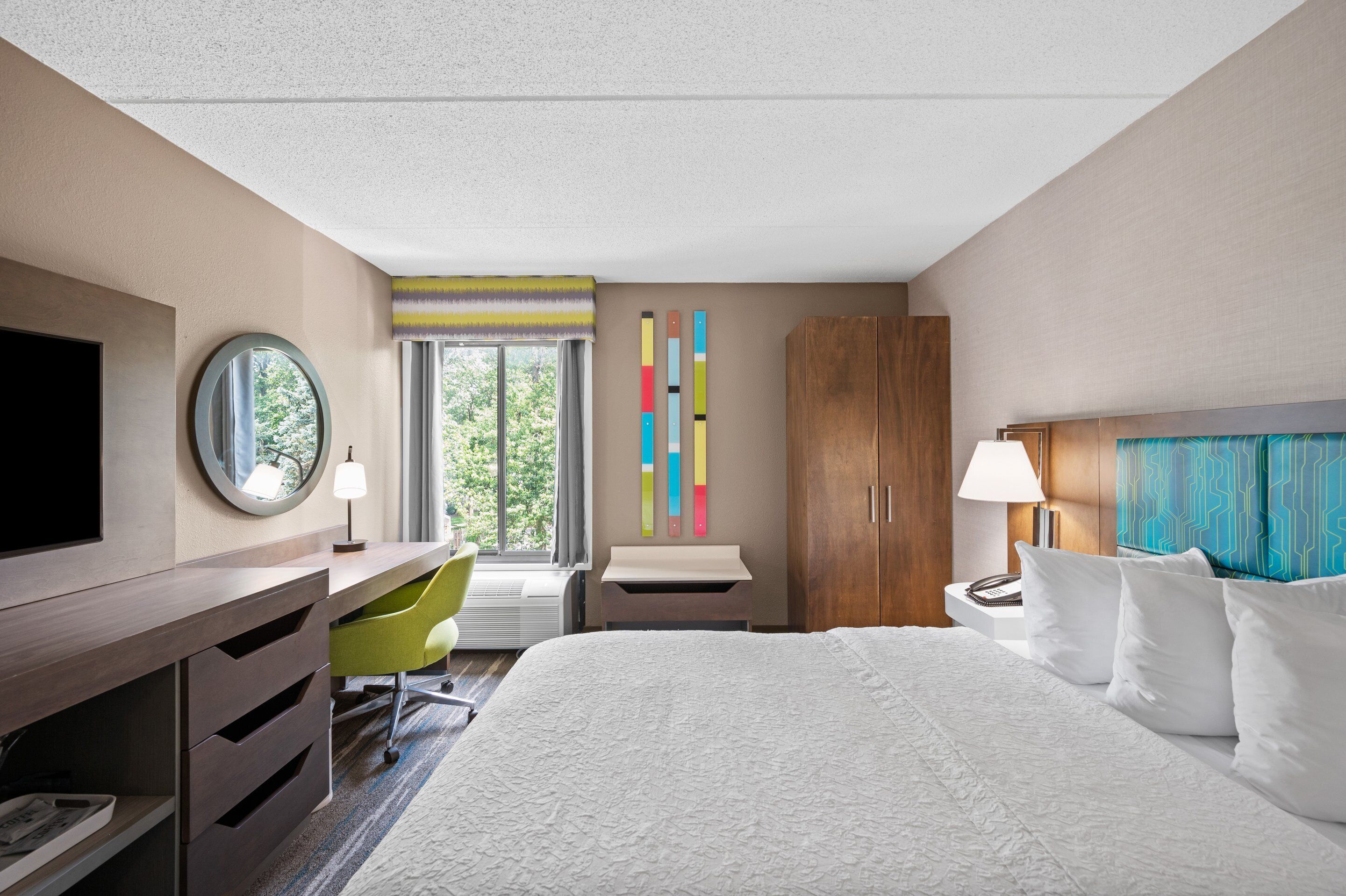 Ein Hotelzimmer mit Bett, Schreibtisch, Stuhl und Fernseher.