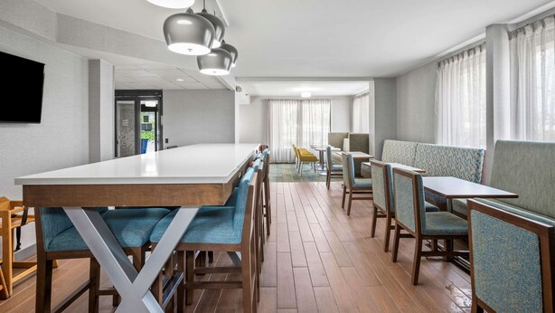 Un comedor moderno con una mesa larga y diversas opciones de asiento, como asientos tipo cabina y sillas.
