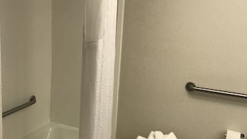 Un baño con ducha, inodoro y barra de apoyo.