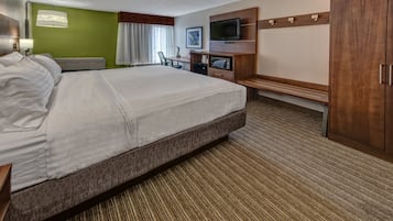 Quarto de hotel com uma cama grande, uma escrivaninha com televisão de tela plana, micro-ondas e um guarda-roupa.