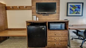 A compact kitchenette with a refrigerator, microwave, and a flat-screen TV.
