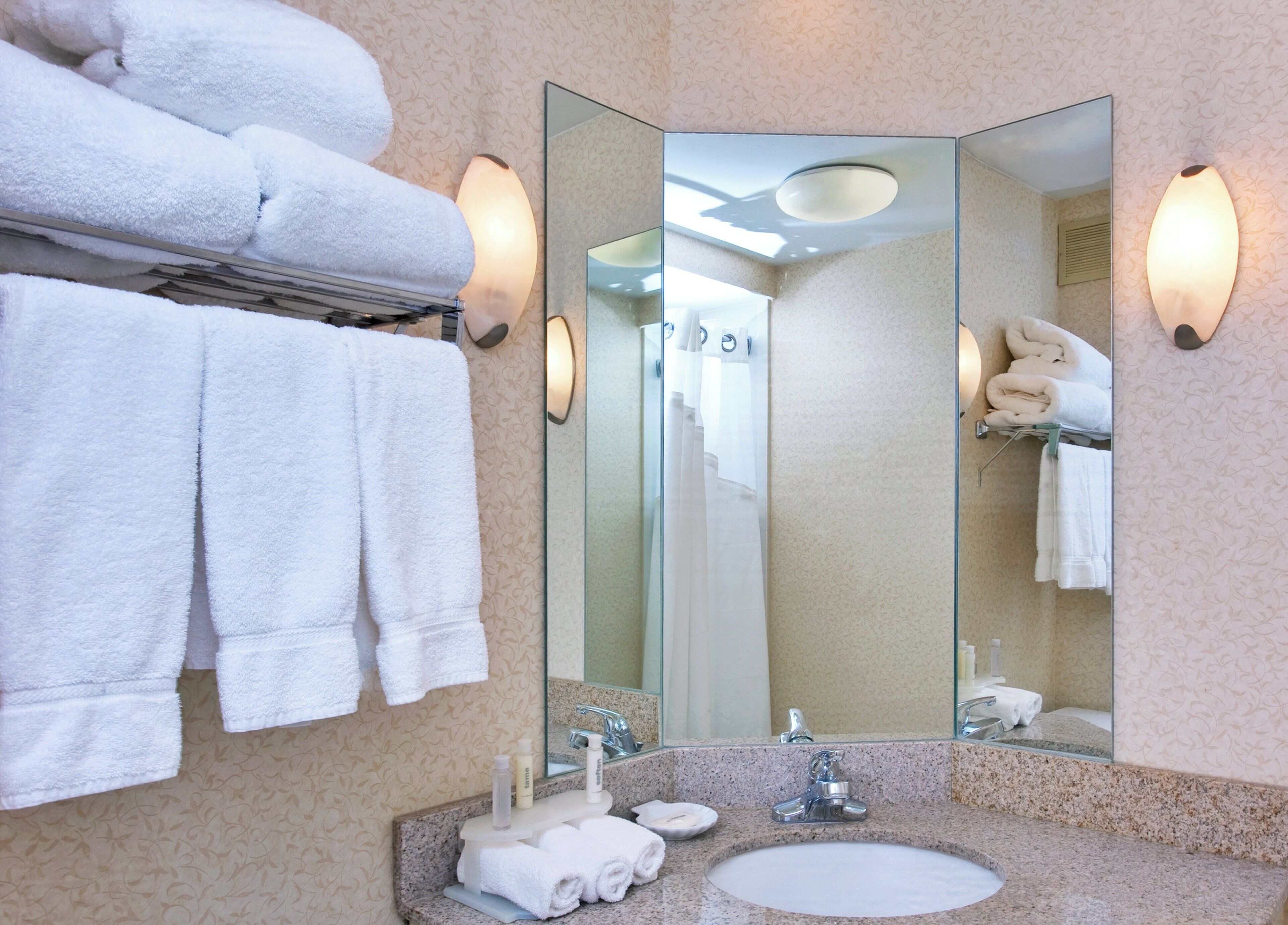 A bathroom with a sink, mirror, towel rack, and wall sconces.