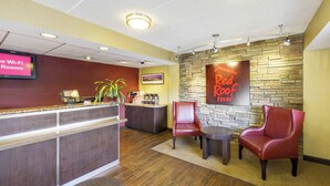 Zona de recepción de Red Roof Inn con mostrador, asientos y una pared de piedra.