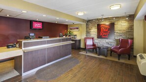 A hotel reception area with a digital display, a reception desk, a seating area with chairs, and a Red Roof Inn sign on the wall. - Red Roof Inn Richmond South (Richmond)