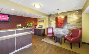 Zona de recepción de Red Roof Inn con mostrador, asientos y una pared de piedra.