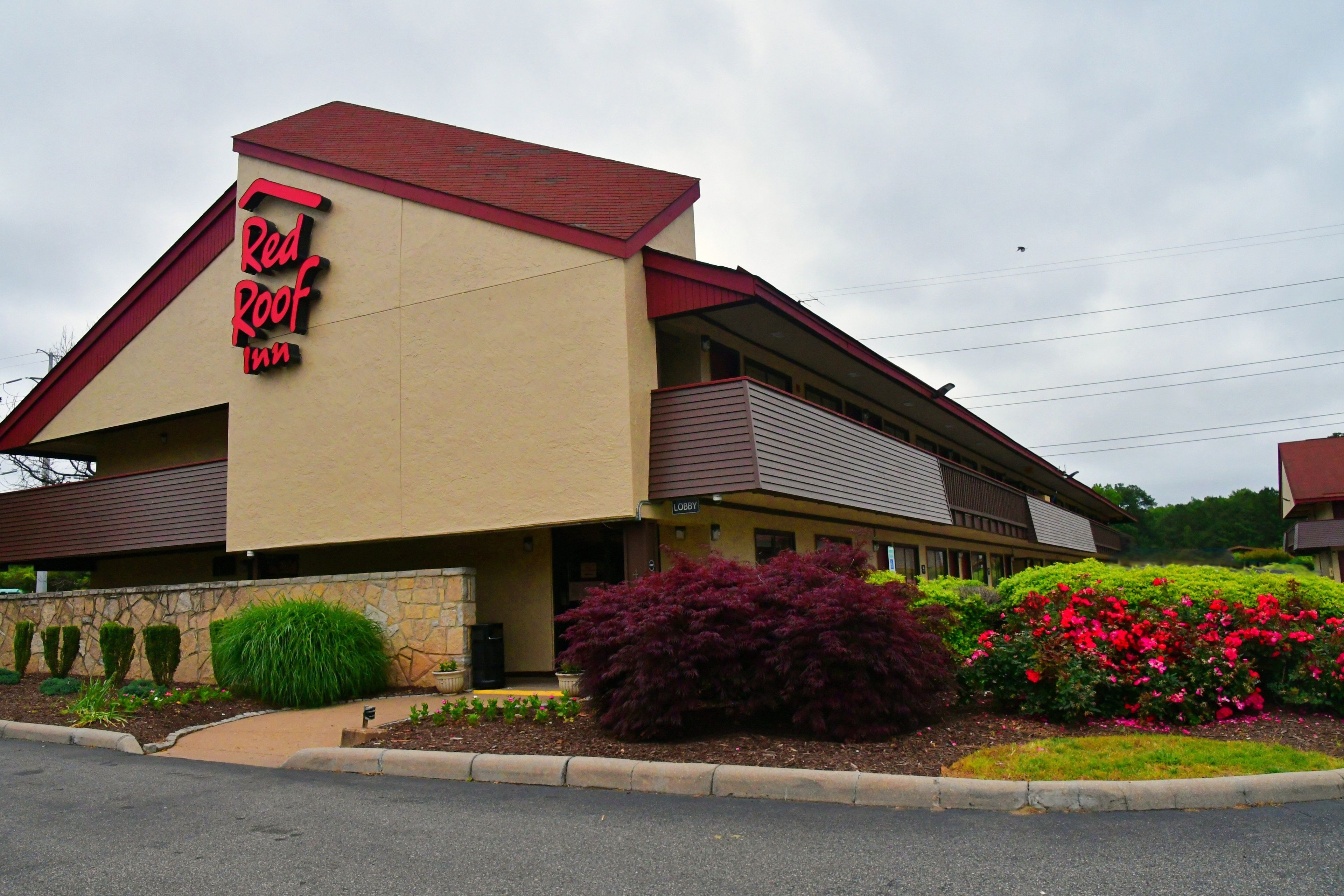 A Red Roof Inn with a red roof, beige walls, and a signboard.