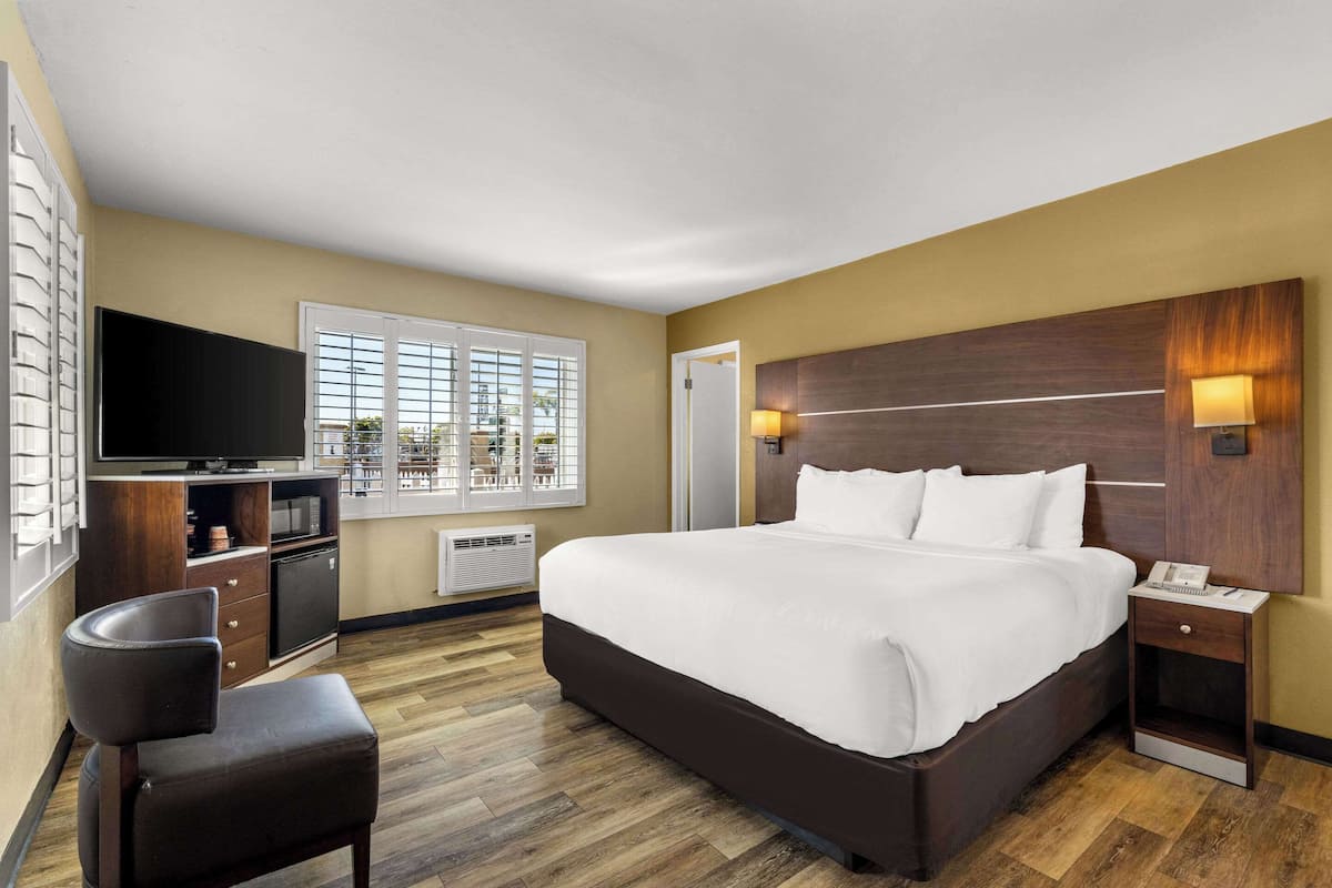 Habitación de hotel con una cama grande, televisión, escritorio y una silla.