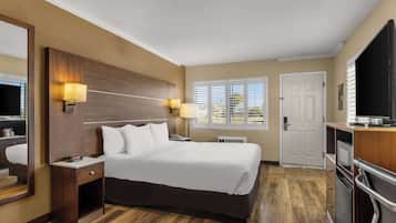 A hotel room with a large bed, bedside lamps, a TV, and a view of the outdoors through the window.