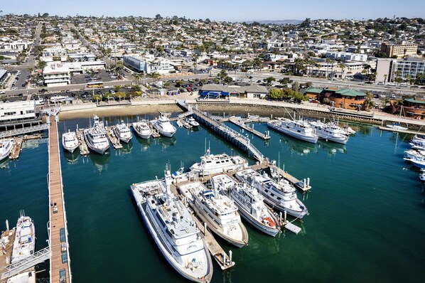 A marina with multiple boats docked, surrounded by residential buildings and a clear sky.
