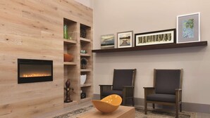 A modern living room with a fireplace, two armchairs, a coffee table, and a bookshelf. - Country Inn & Suites by Radisson, London, KY (London)