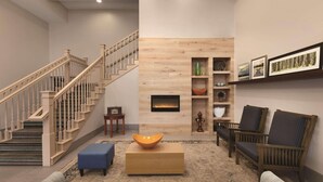 A modern living room with a staircase, a fireplace, and a coffee table. - Country Inn & Suites by Radisson, London, KY (London)