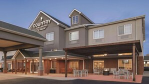 A Country Inn & Suites by Radisson building with a covered outdoor seating area and brick facade. - Country Inn & Suites by Radisson, London, KY (London)