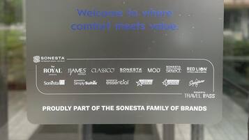 Señal del Americas Best Value Inn por Sonesta, que muestra un logotipo de estrella y varios logotipos de marca, incluyendo The Royal Sonesta, The James y Red Lion.