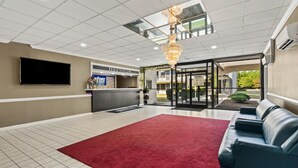 A reception area with a registration desk, a red carpet, and a blue leather couch. - Americas Best Value Inn Wilson (Wilson)