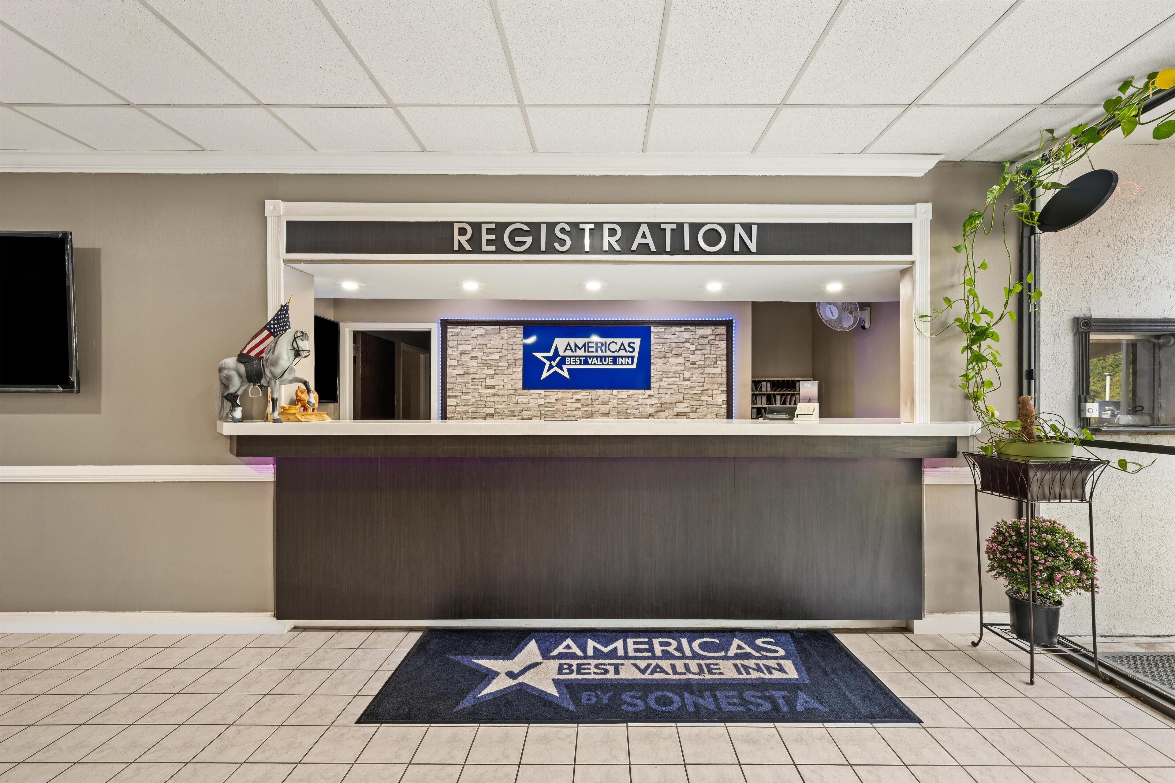 Een hotel receptie met een bordje voor 'AMERICAS BEST VALUE INN' en een welkomstmat in de vorm van een ster.