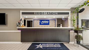 Een hotel receptie met een bordje voor 'AMERICAS BEST VALUE INN' en een welkomstmat in de vorm van een ster.