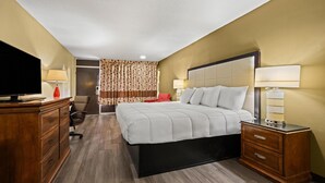 A hotel room with a large bed, wooden dresser, and a television on the left. - Americas Best Value Inn Wilson (Wilson)