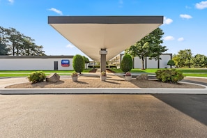 A gas station with a canopy, a sign indicating '1815 A', and landscaped areas with bushes and rocks.