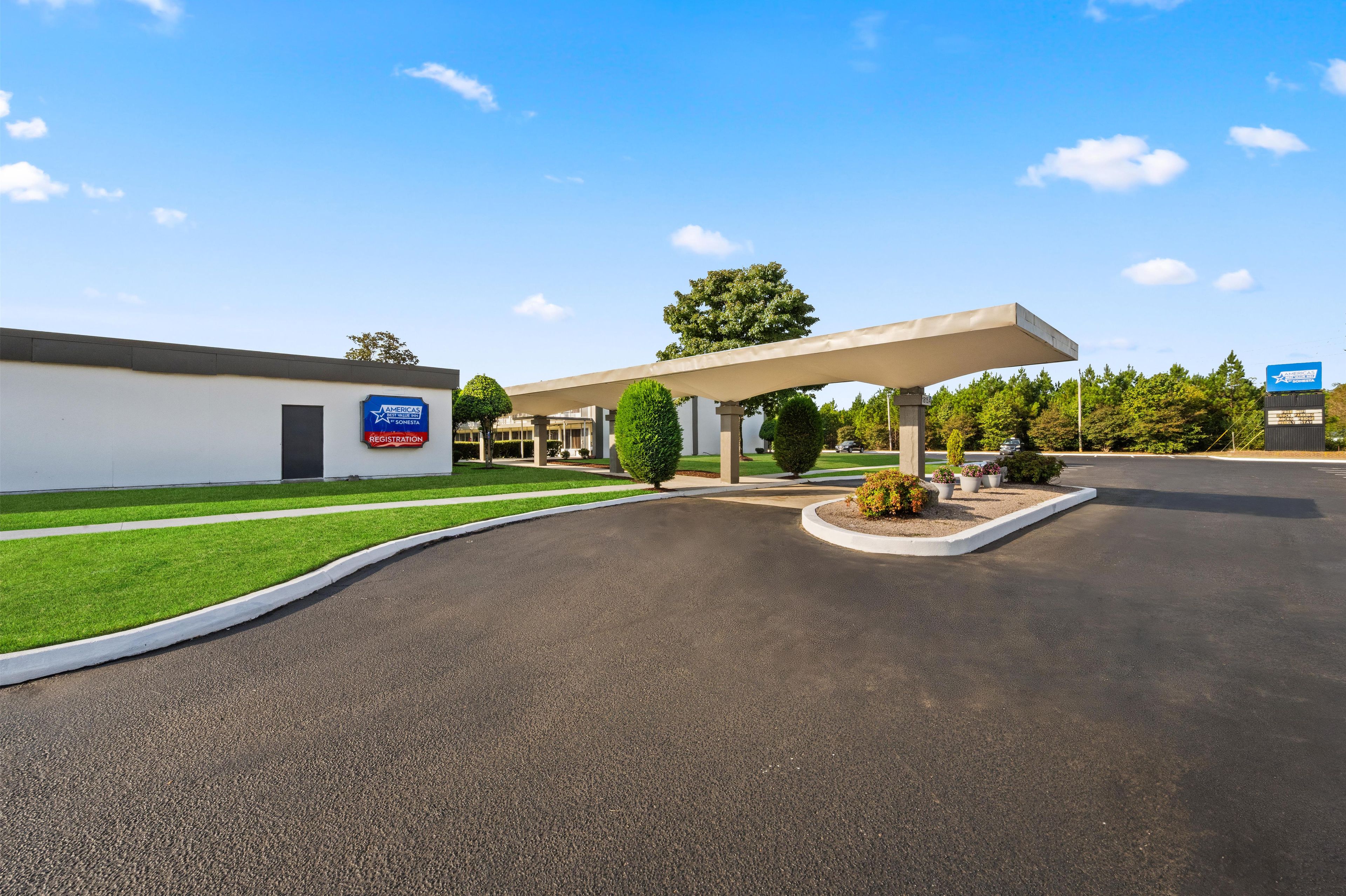 A gas station with a canopy, a registration sign, and a building with a sign.