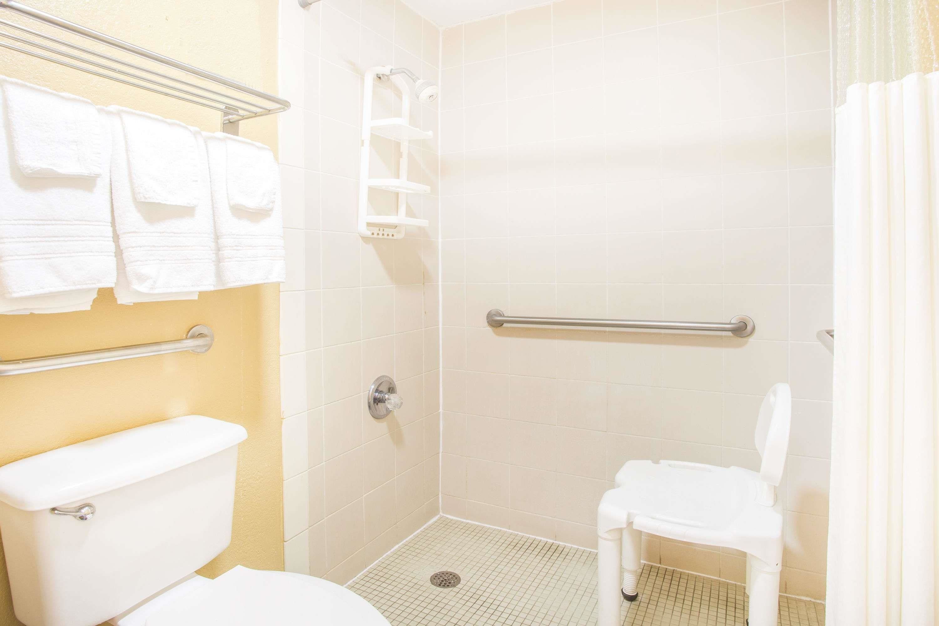 Un baño pequeño para una sola persona, con inodoro, ducha y barra de apoyo.