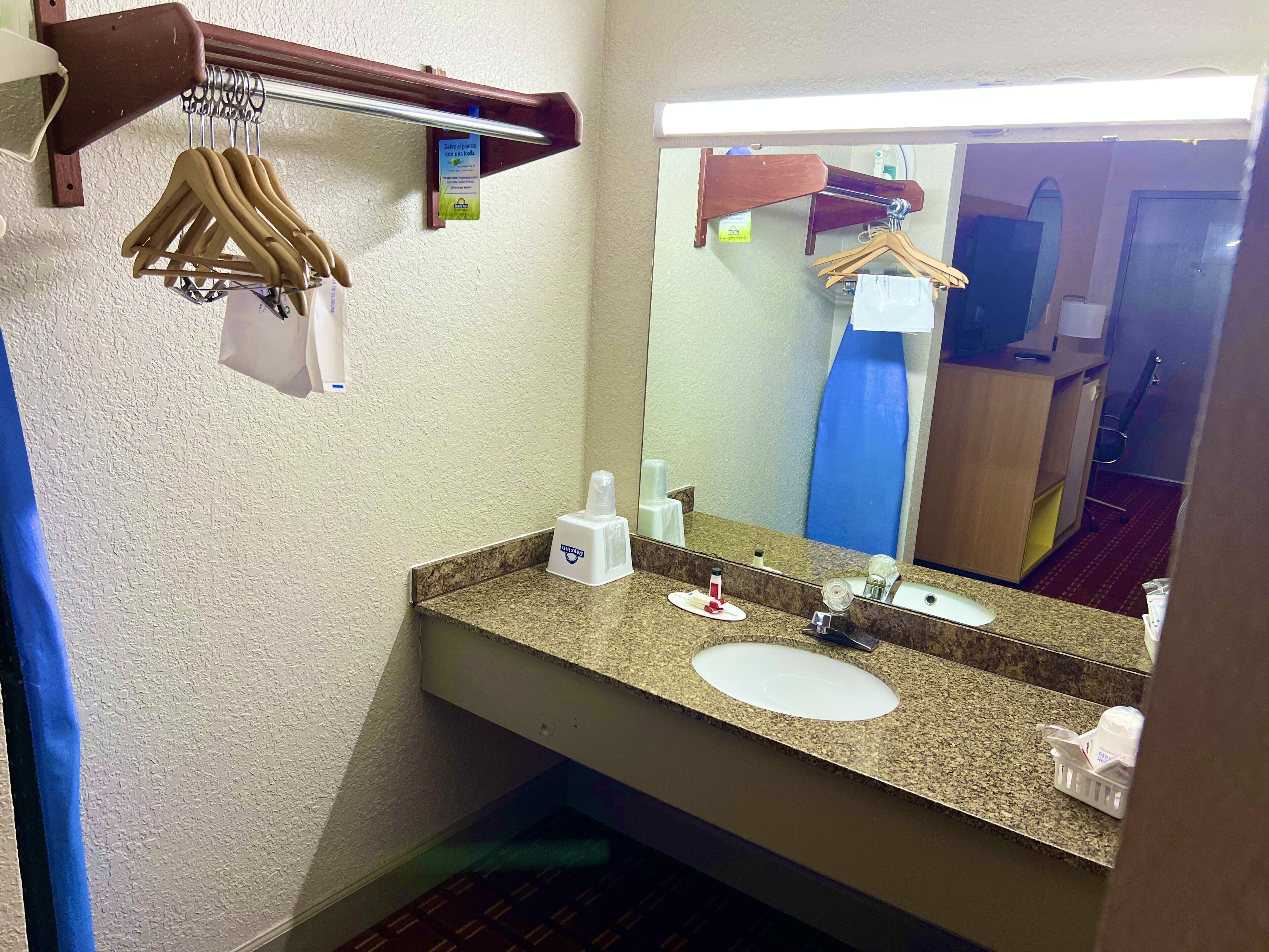 A bathroom with a granite countertop, a sink, a mirror, and a towel rack.