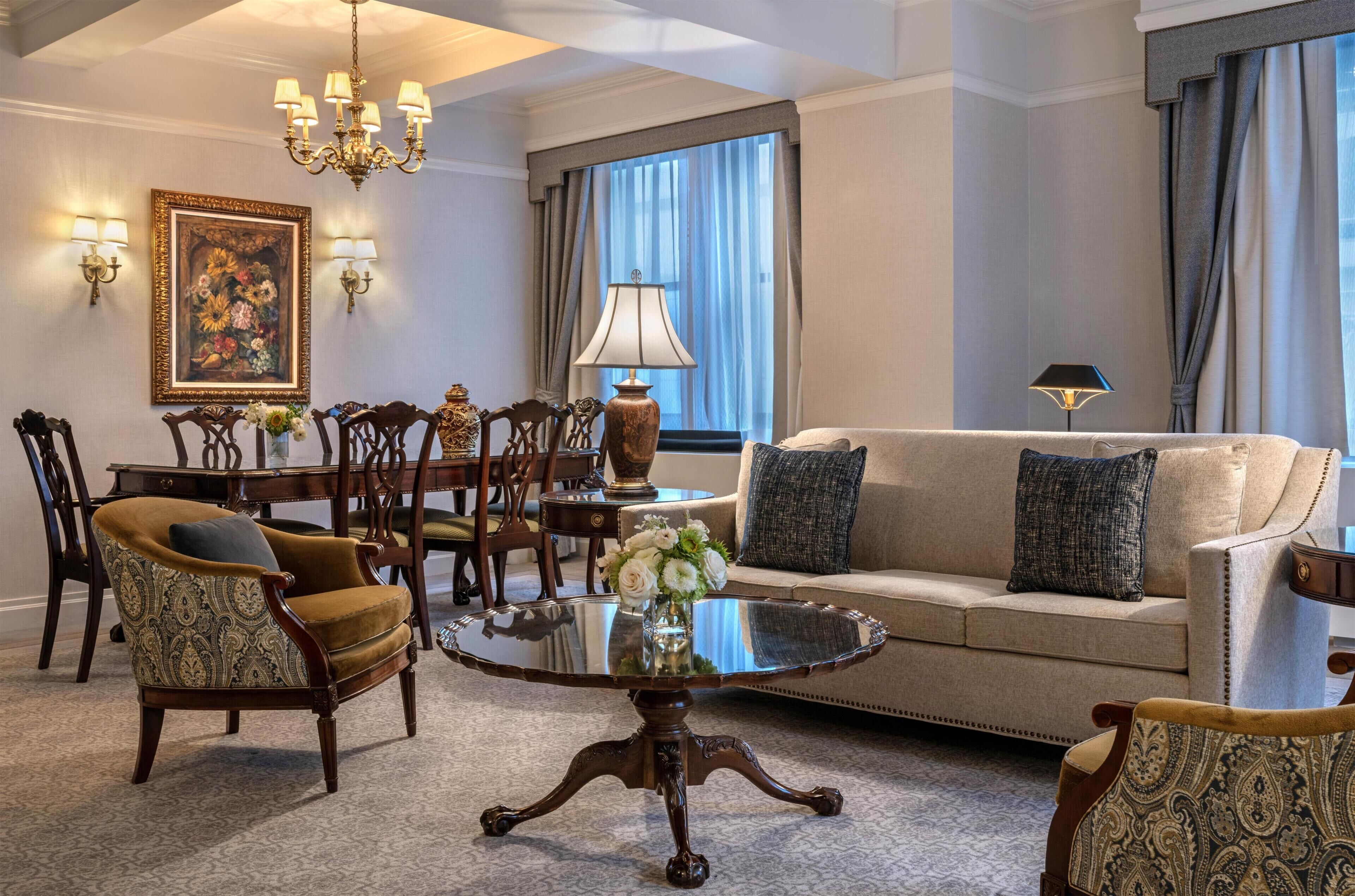 A well-appointed living room with a sofa, armchairs, a dining table, and a chandelier.
